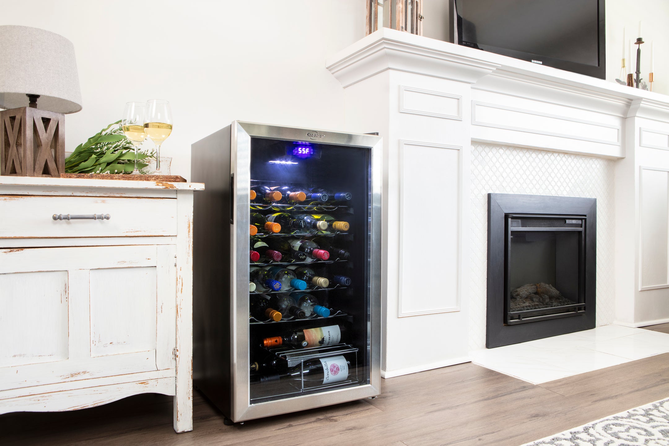 50 Bottle Wine Fridge in a living room beside a fireplace and console. Text reads " Technology meets style. See our full range of Wine coolers. Shop Now"  