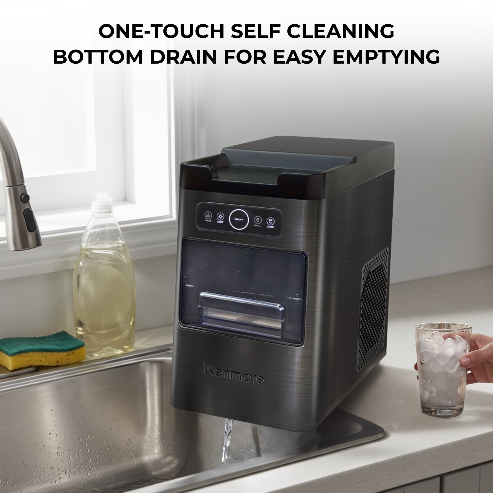 Kenmore front load automatic ice maker on the side of a sink with water coming out of the drain on the bottom. Text above reads, "One-touch self cleaning: Bottom drain for easy emptying"