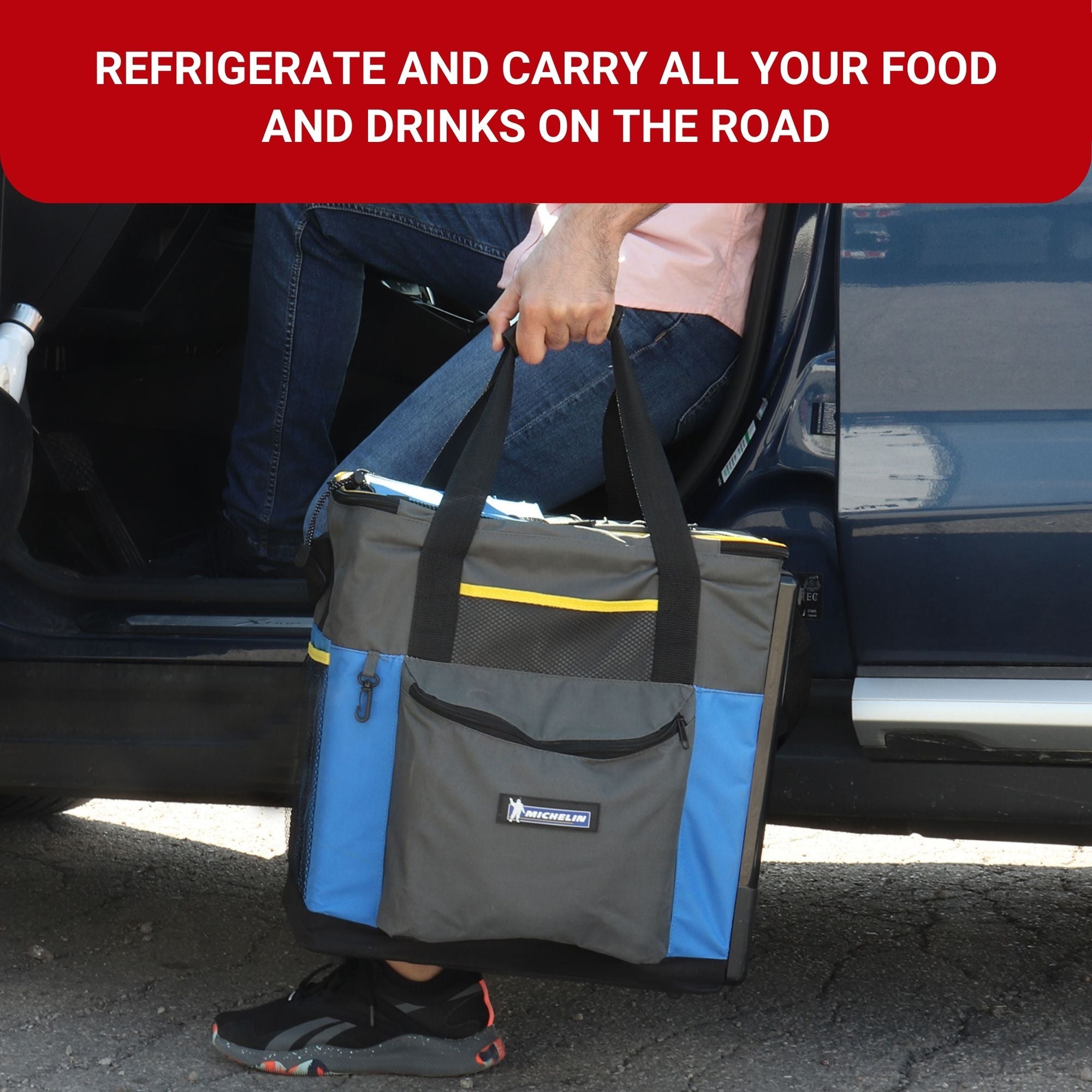 A person holding the Michelin portable 12V cooler/warmer bag by the handles stepping into a pickup truck. Text above reads, "REFRIGERATE AND CARRY ALL YOUR FOOD AND DRINKS ON THE ROAD"