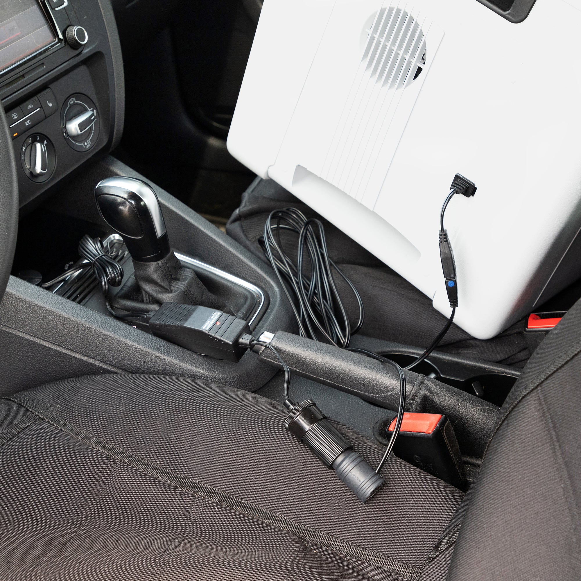 Koolatron 12V Car Battery Saver connected to a 12 volt cooler on the front passenger seat of a car with black upholstery