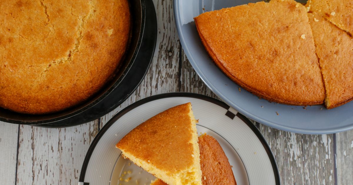 Closeup photo of round loaves and wedges of golden-brown cornbread on plates viewed from above