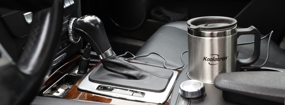 Lifestyle image of 12V heating travel mug in the cupholder of a car with black leather upholstery