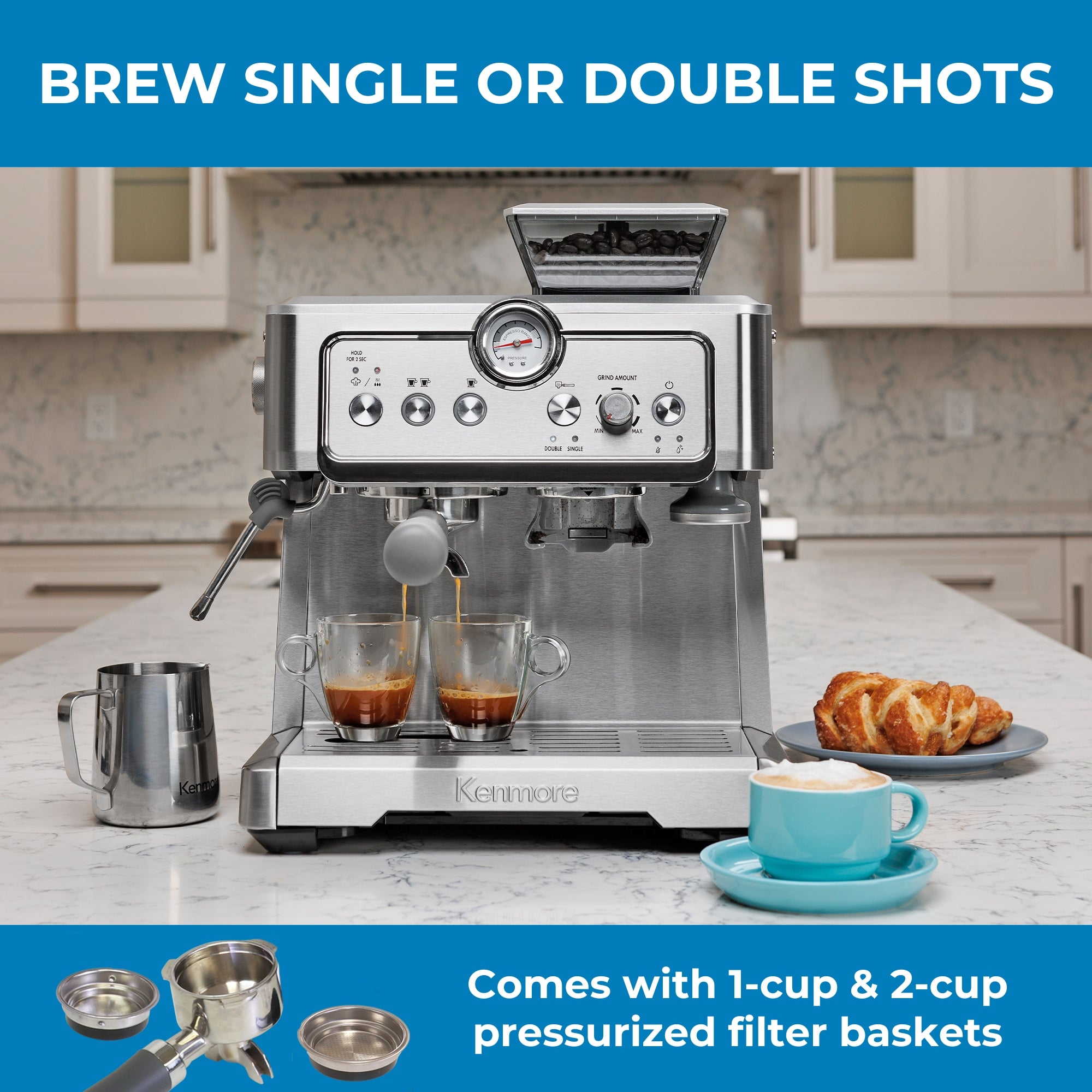 Kenmore semi-automatic espresso maker with espresso being extracted into two clear cups on a white marble countertop with the milk pitcher, a pastry, and a cappuccino in a light blue mug arranged around it. Text above reads, "Brew single or double shots," and text below reads, "Comes with 1-cup and 2-cup pressurized filter baskets" accompanied by an inset picture of a portafilter and 2 filter baskets.