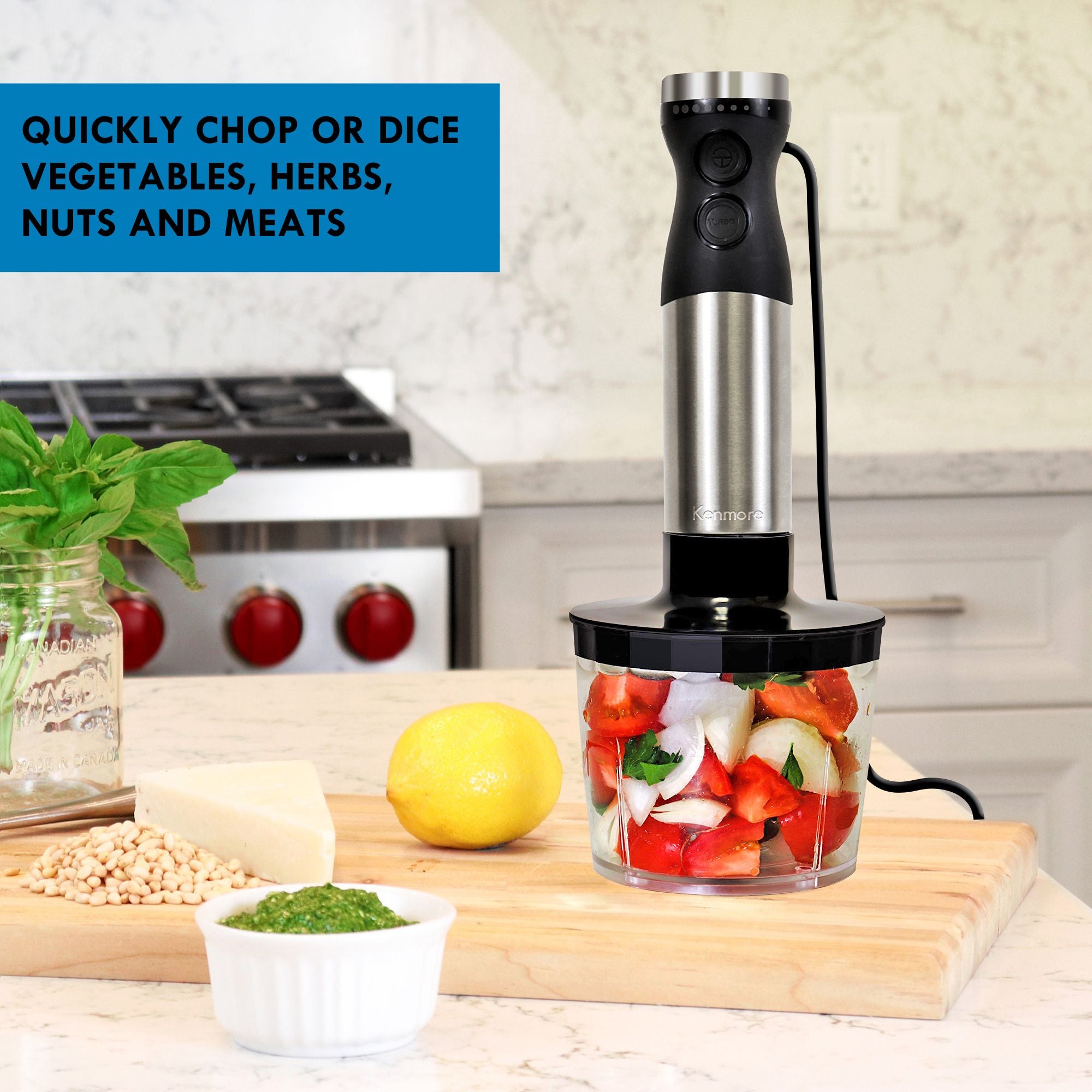 Immersion blender with food chopper attachment filled with cut up peppers, tomatoes, onions, and cilantro on a wooden cutting board with basil, pinenuts, cheese, a lemon, and a small dish of pesto beside it. Text overlay reads Quickly chop and dice vegetables, herbs, nuts, or meat.
