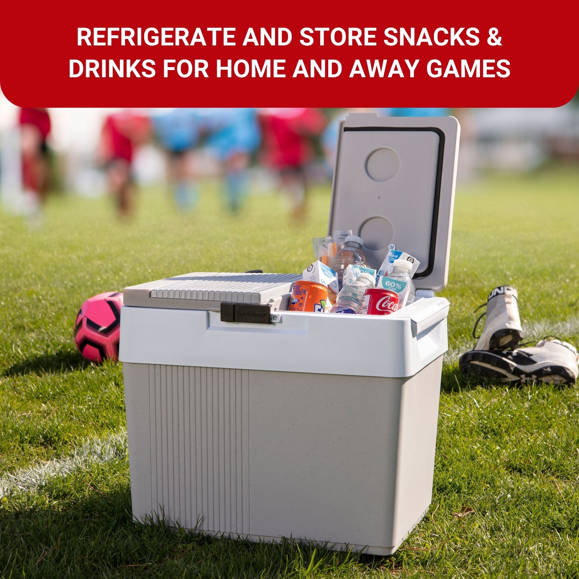 Koolatron portable 12V cooler/warmer filled with drinks with one half of lid open on a grass soccer pitch. Text above reads, "REFRIGERATE AND STORE SNACKS AND DRINKS FOR HOME AND AWAY GAMES"