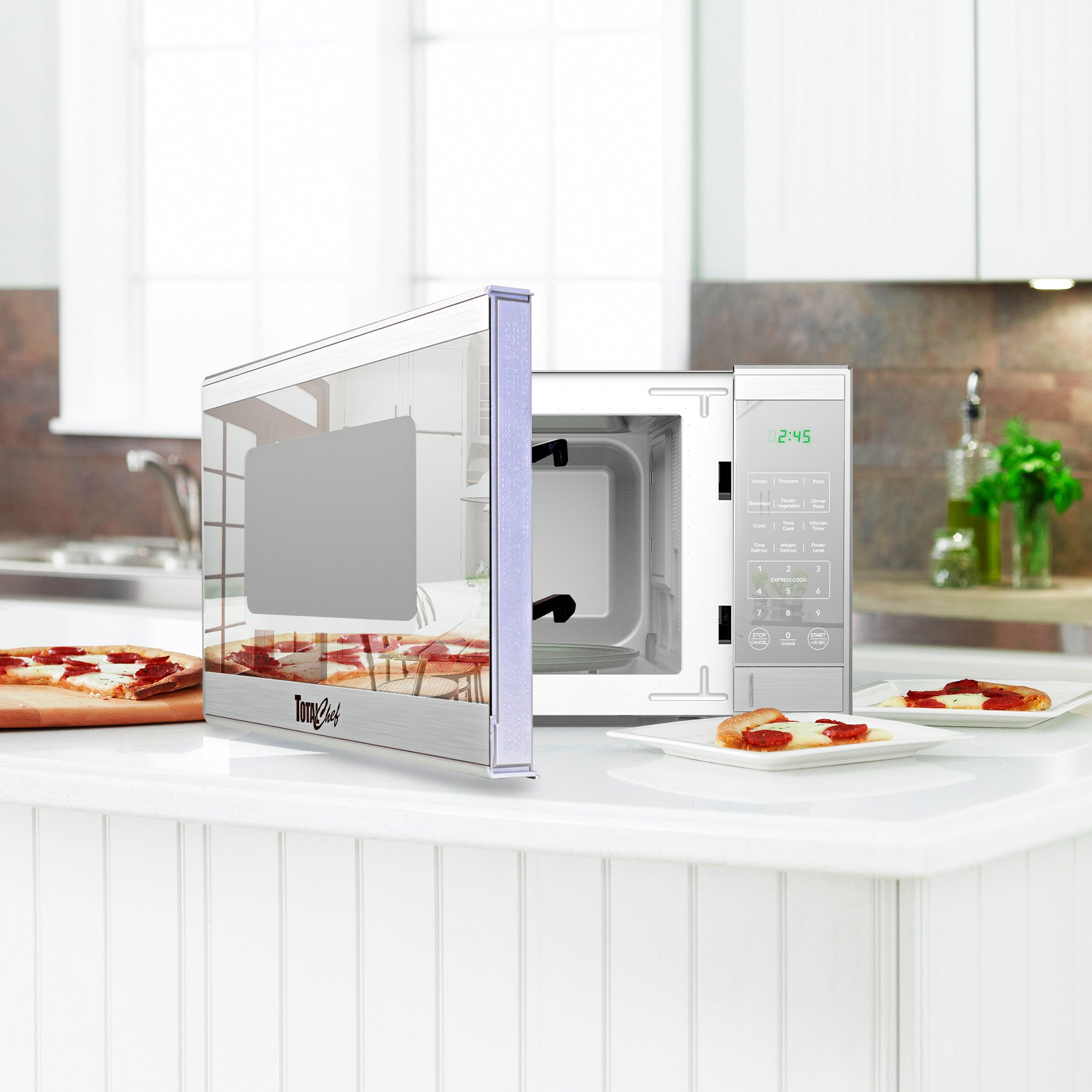Total Chef stainless steel microwave, partly open, with slices of pizza on plates arranged around it on a white counter in a modern-looking kitchen