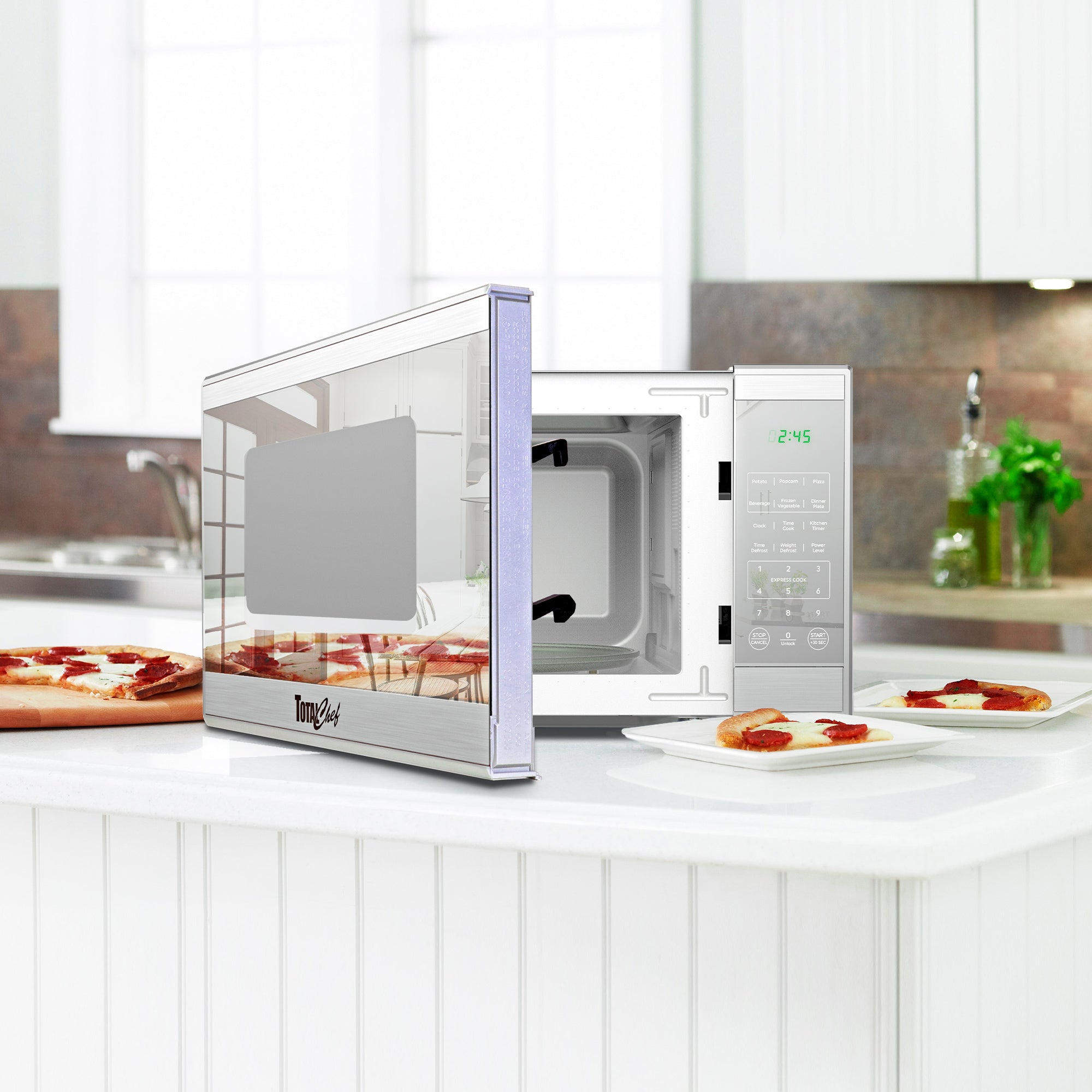 Total Chef stainless steel microwave, partly open, with slices of pizza on plates arranged around it on a white counter in a modern-looking kitchen