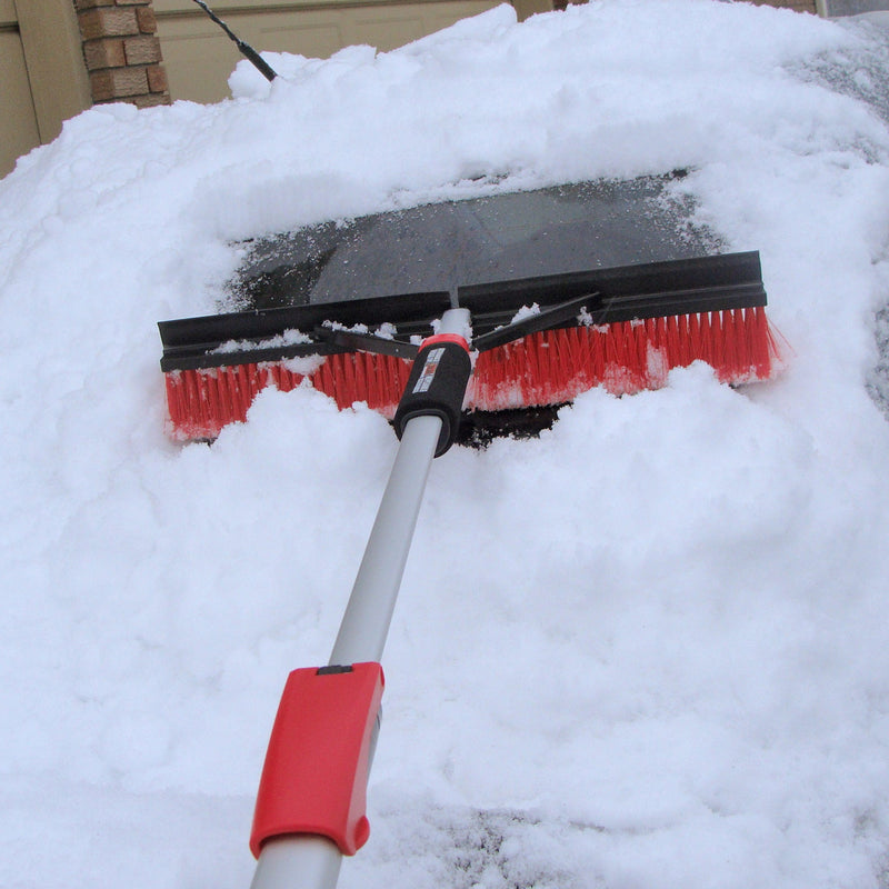 Lifestyle image of the fully expanded brush being used to clear deep snow from the window of a dark coloured car