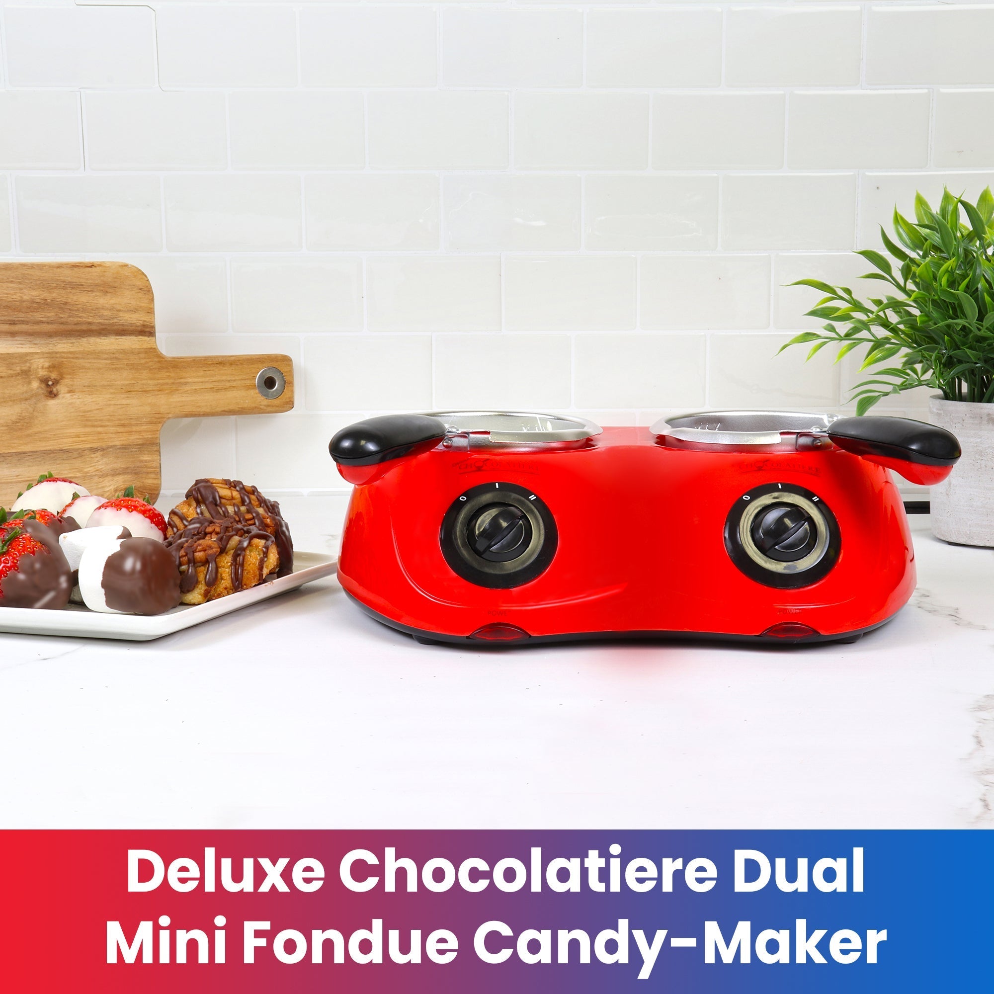 Lifestyle image of double electric chocolate melter on a white counter with a plate of chocolate dipped strawberries and marshmallows to the left. Text below reads, "Deluxe chocolatiere mini fondue candy-maker"