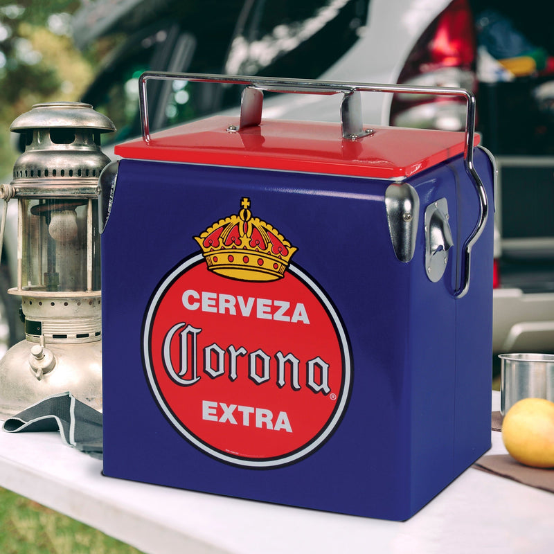 Lifestyle image of Corona retro ice chest with bottle opener on a white folding table with a metal lantern beside it and a vehicle in the background