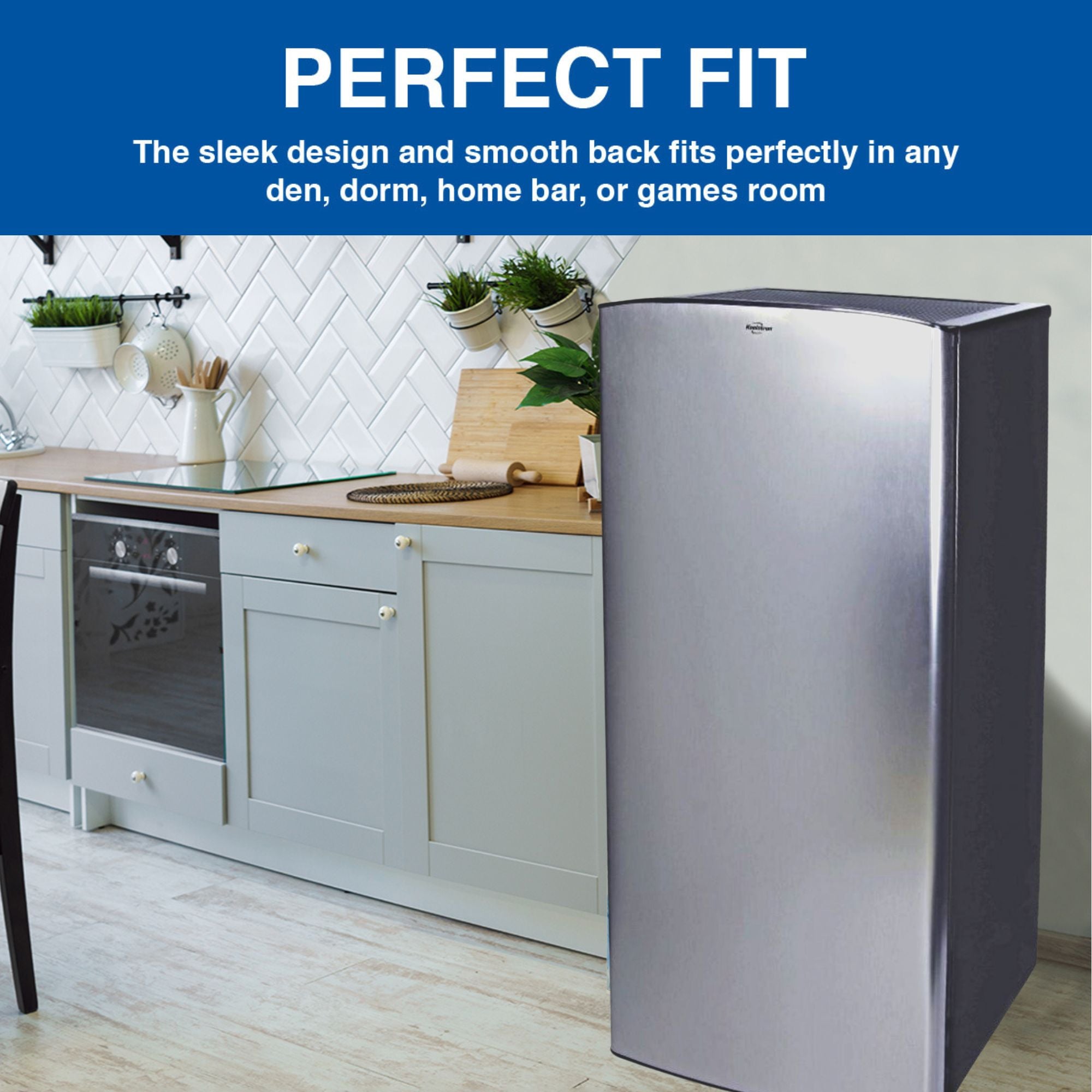 Lifestyle image of black and stainless steel compact fridge with freezer to the right of light gray kitchen cupboards with a wooden countertop, white tile backsplash, and hanging plants. Text above reads, "Perfect fit: The sleek design and smooth back fits perfectly in any den, home bar, or games room"