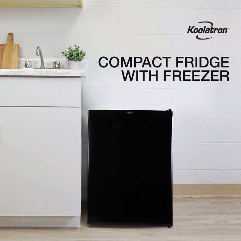 Lifestyle image of black compact fridge with freezer beside a white kitchen cabinet with white and gray marble countertop. Text above reads "Koolatron stainless steel compact fridge with freezer"