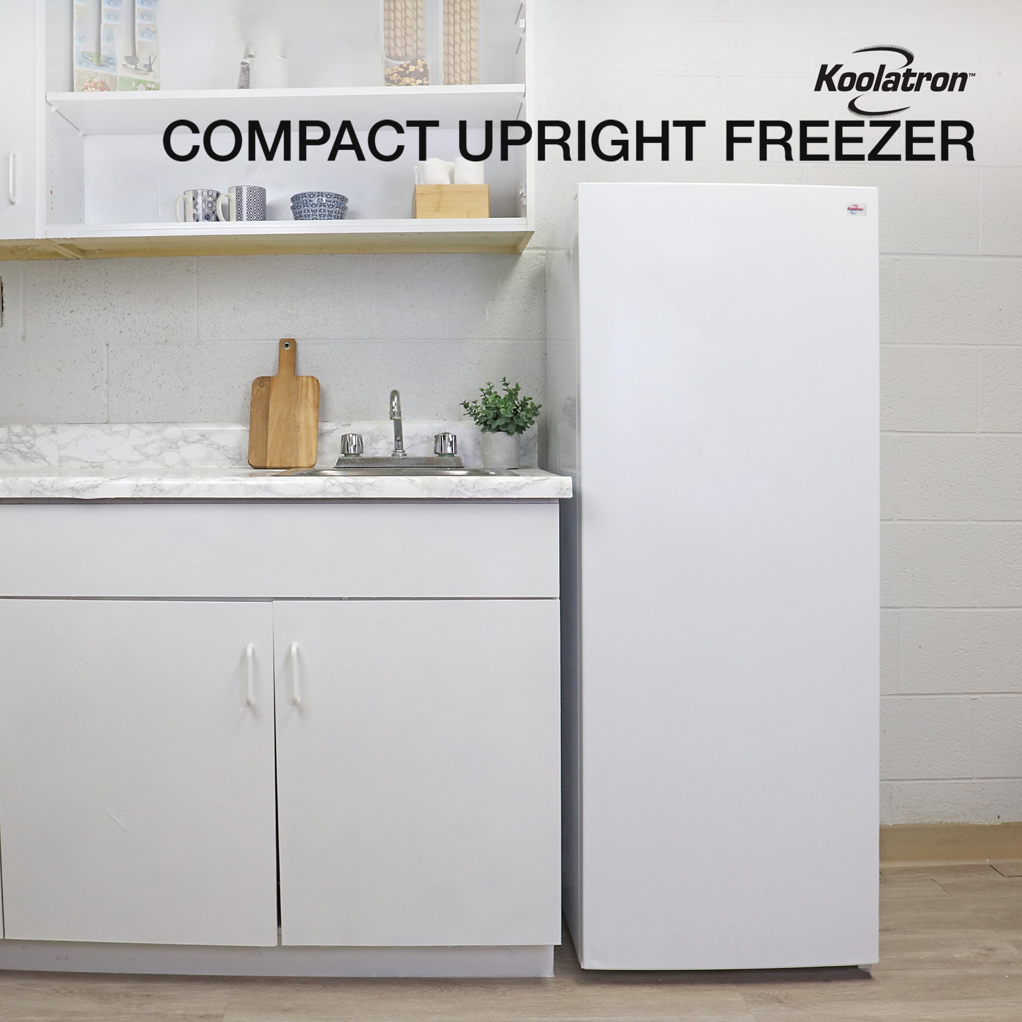 Lifestyle image of upright freezer beside a white kitchen cabinet with white marble countertop. Text above reads "Koolatron compact upright freezer"