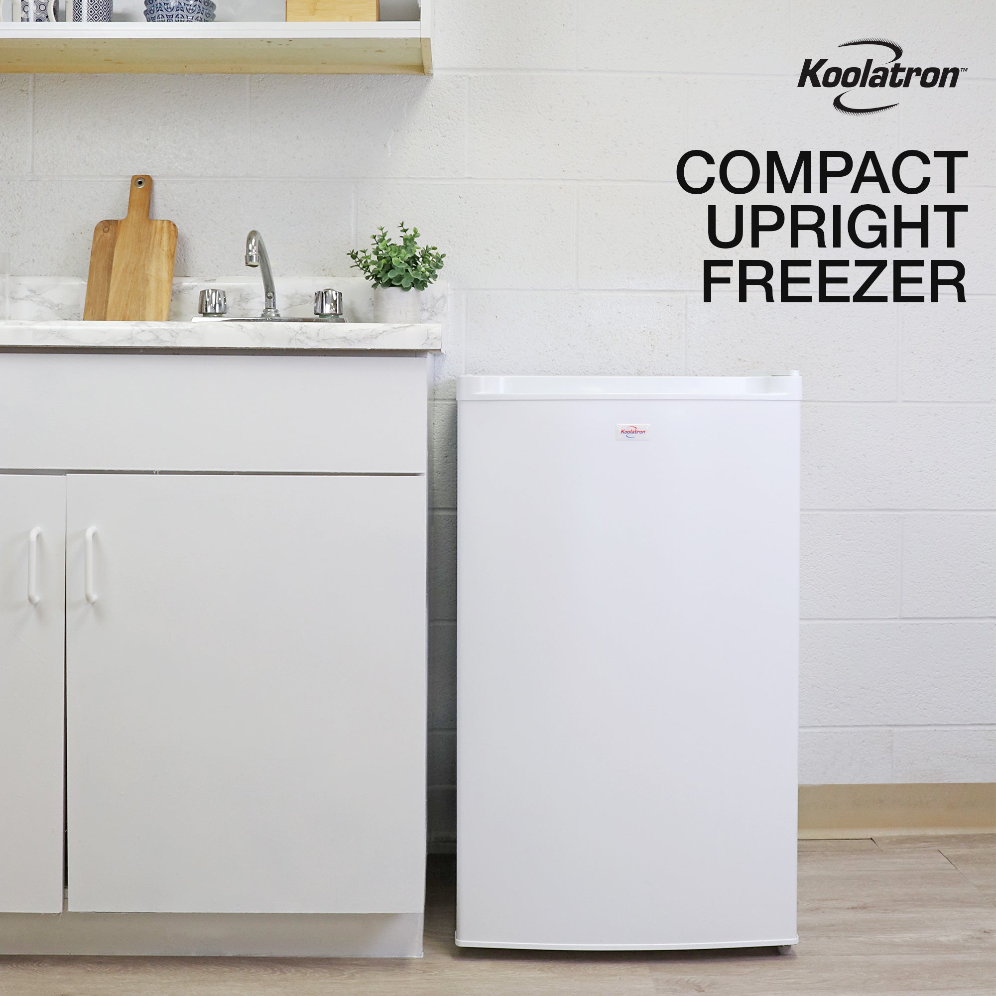 Lifestyle image of upright freezer beside a white kitchen cabinet with white marble countertop. Text above reads "Koolatron compact upright freezer"