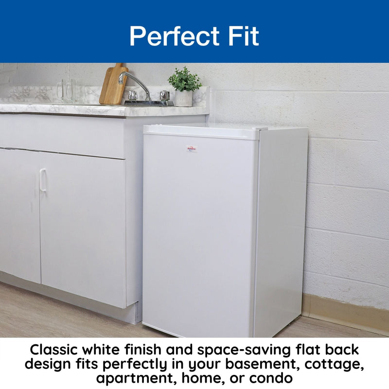 Lifestyle image of closed upright freezer on a light-colored wood floor beside a white kitchen cabinet with marble countertop. Text above reads, "Perfect fit," and text below reads, "Classic white finish and space-saving flat back design fits perfectly in your basement, cottage, apartment, home, or condo"
