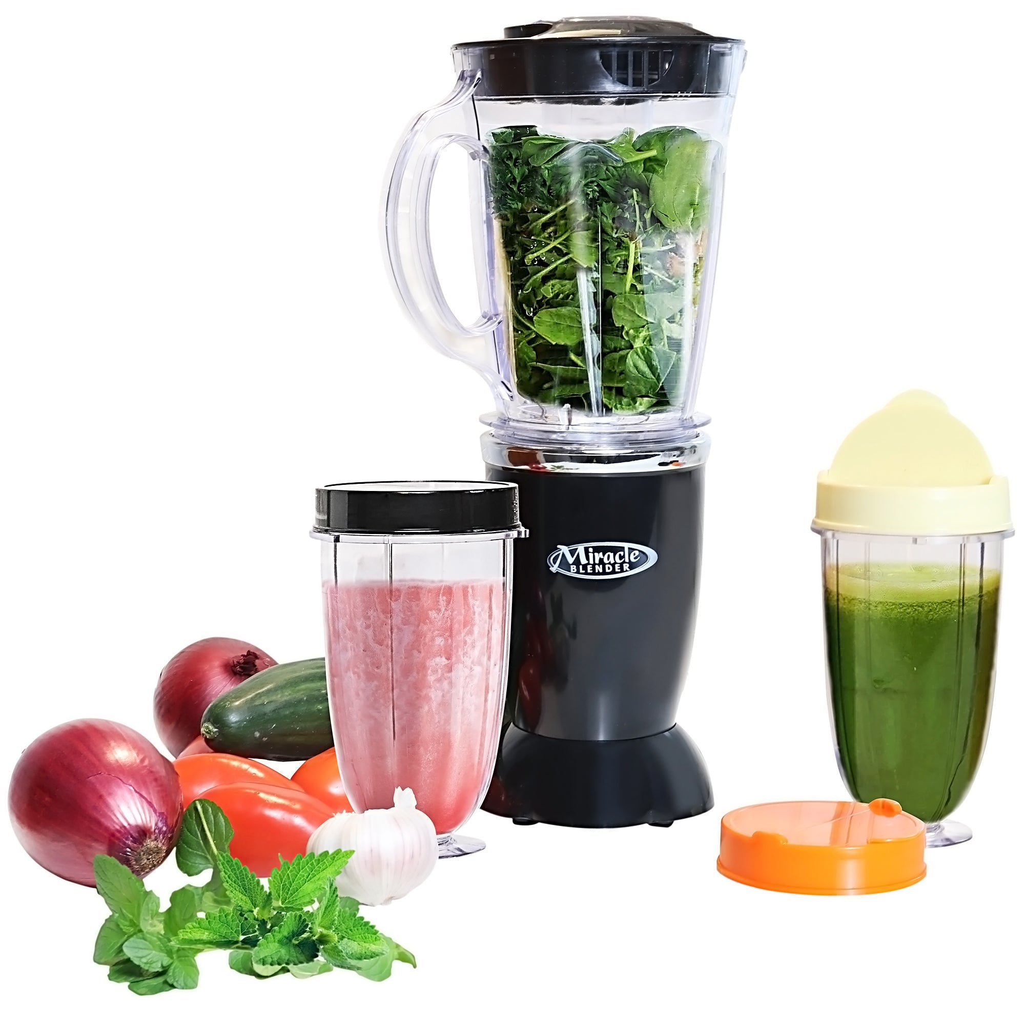 Product shot of blender with pitcher filled with green vegetables, two personal cups with lids filled with pink and green smoothie, and vegetables beside