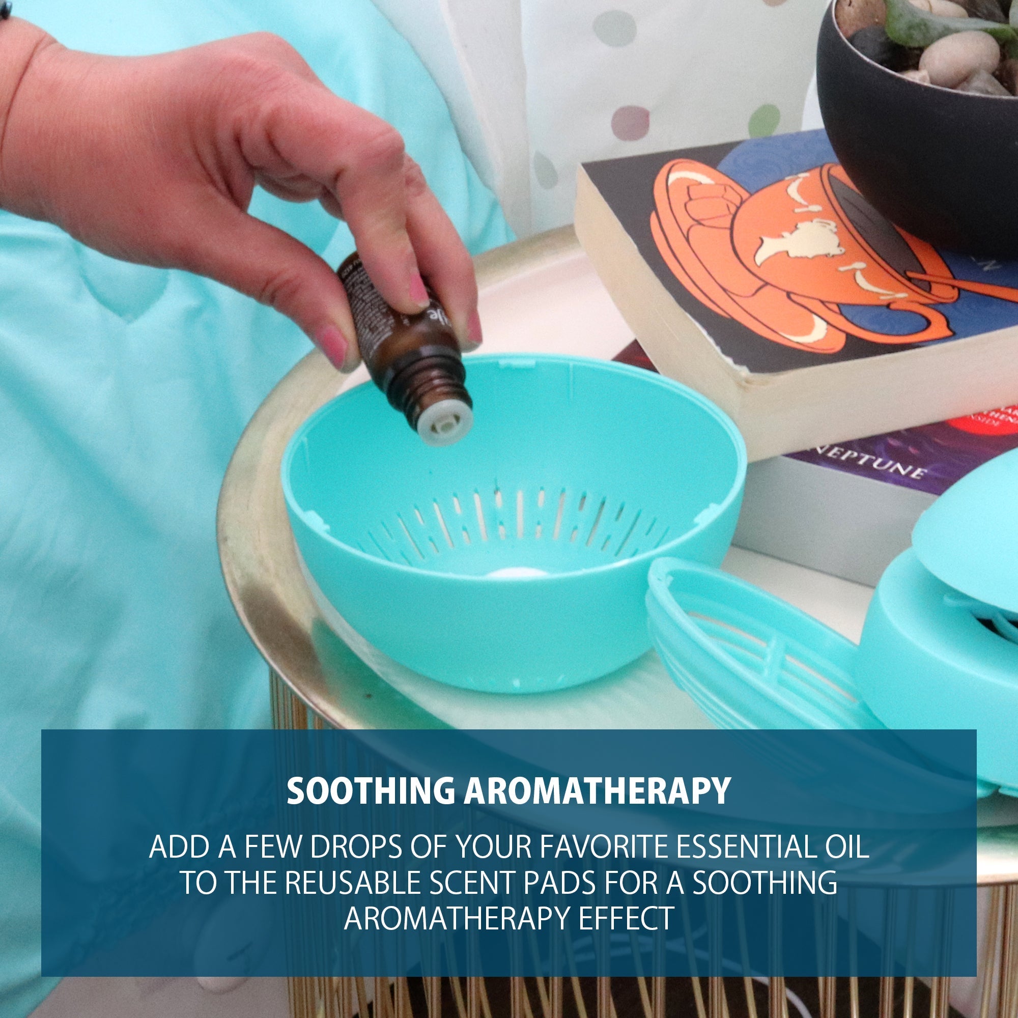 Lifestyle image of the bottom portion of the indoor insect trap on a bedside table surrounded by the other parts of the trap, two books, and a black ceramic bowl. A person's hand is holding an open essential oil bottle to apply drops to the scent pad. Text below reads, "Soothing aromatherapy: Add a few drops of your favorite essential oil to the reusable scent pads for a soothing aromatherapy effect"