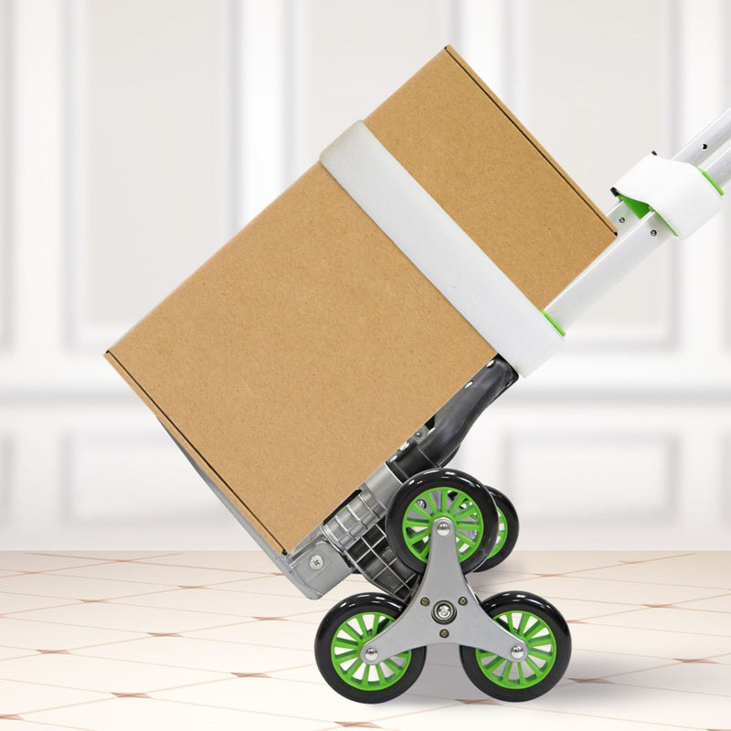 Lifestyle image of the foldable hand truck with a large cardboard box on it secured with a safety strap