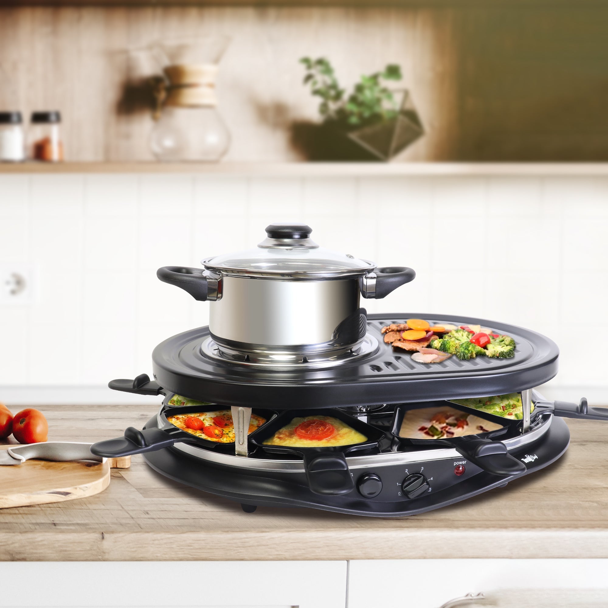 Product shot of raclette and fondue set on white background with various types of food being grilled or warmed, including sausages, broccoli, fried egg, and cheese, plus a plate of meat and vegetables